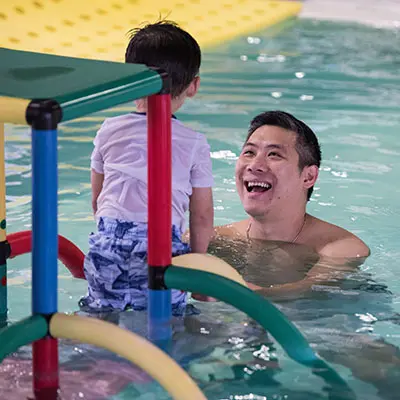 Father smiling at son in the pool