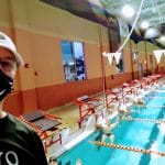 swim coach wearing mask and swimmers in background