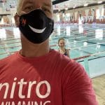 coach mike wearing mask with swimmer in background