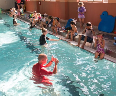 Swim instructor giving lessons to a group of children