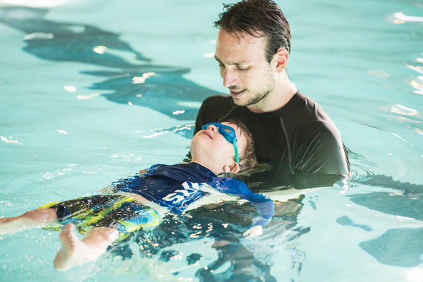 Child learning to float in the pool at swim lessons