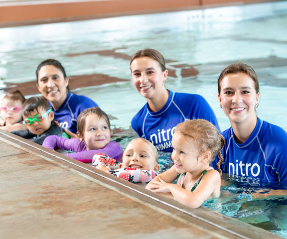 swim instructors working with kids in lessons
